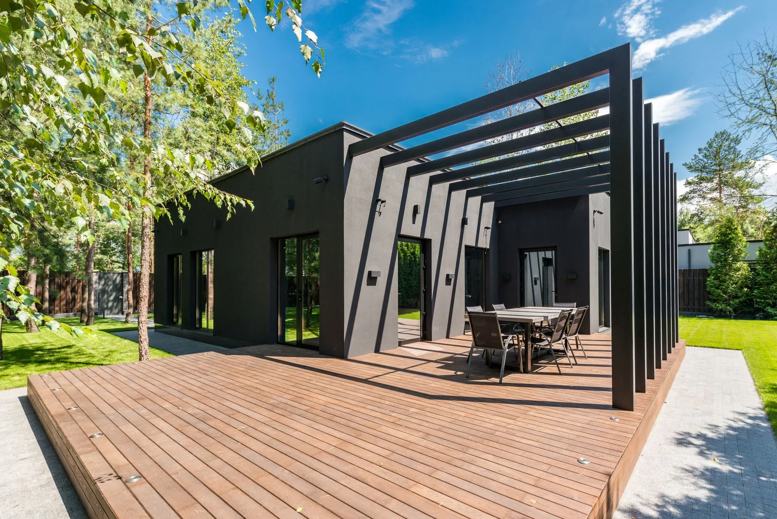 Modern wood deck and pergola beside a dark home